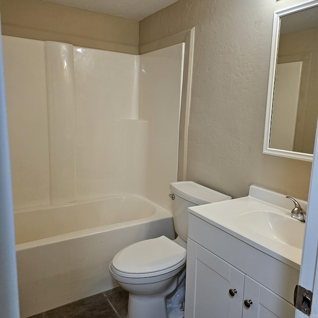 bathroom with vanity, a textured wall, tub / shower combination, and toilet