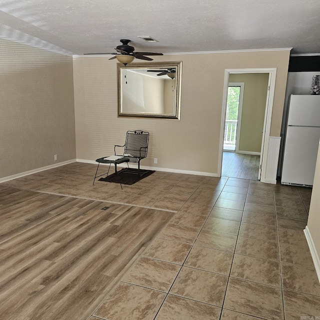 tiled spare room with visible vents, ornamental molding, a textured ceiling, and ceiling fan