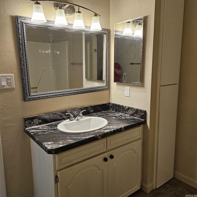 bathroom with vanity, a textured wall, and tile patterned floors