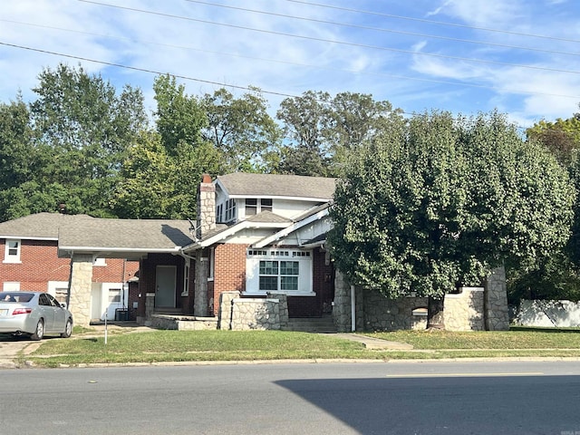 view of front of home featuring brick siding, a chimney, a shingled roof, and a front yard