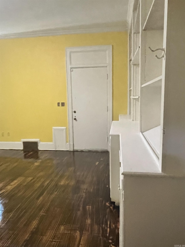interior space featuring dark wood-type flooring, ornamental molding, and baseboards