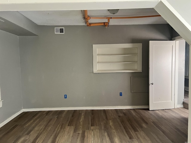 spare room featuring visible vents, baseboards, and wood finished floors