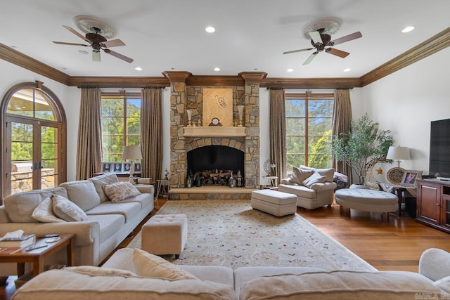 living area featuring crown molding, a wealth of natural light, a ceiling fan, and wood finished floors