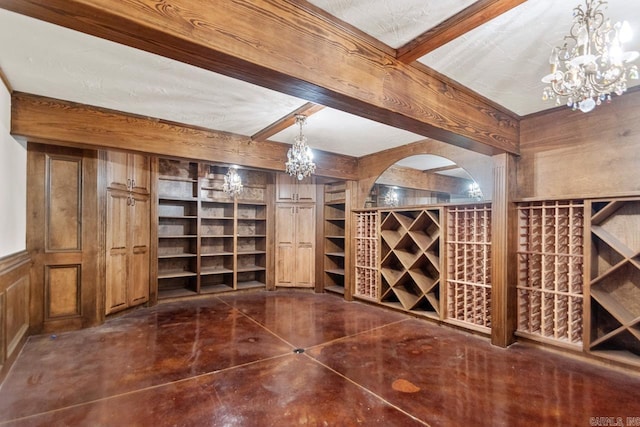 wine cellar with a chandelier, wooden walls, beamed ceiling, and built in shelves