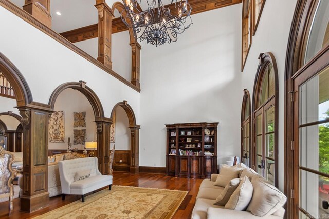 sitting room featuring a notable chandelier, hardwood / wood-style floors, decorative columns, and a towering ceiling