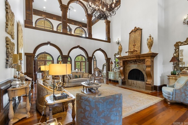 living area with wood finished floors, a towering ceiling, and ornate columns