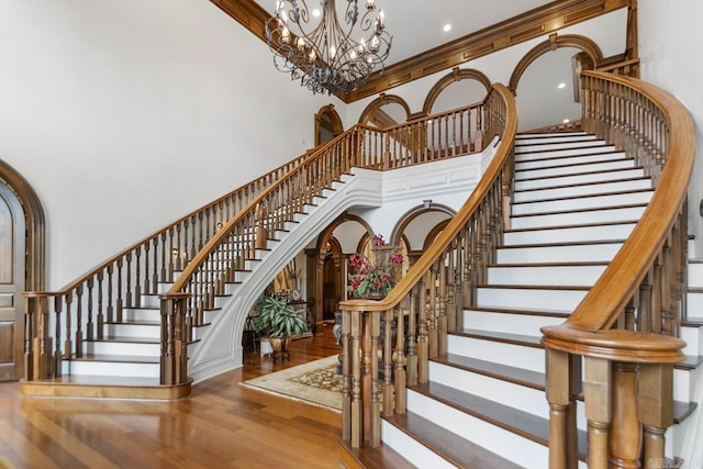 staircase featuring an inviting chandelier, recessed lighting, a towering ceiling, and wood finished floors