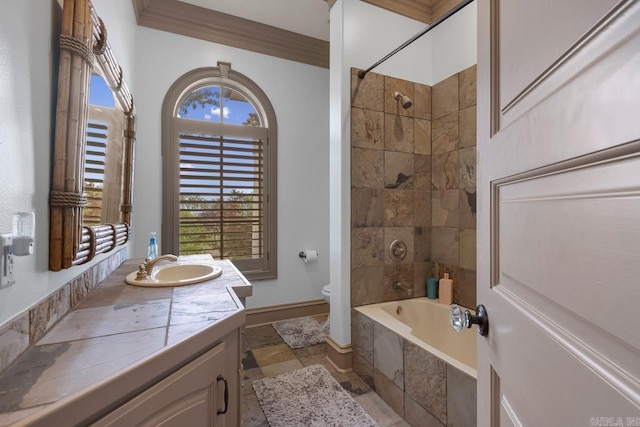 bathroom with tiled shower / bath combo, stone tile floors, toilet, vanity, and crown molding