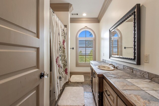 full bath with vanity, stone finish floor, visible vents, crown molding, and baseboards