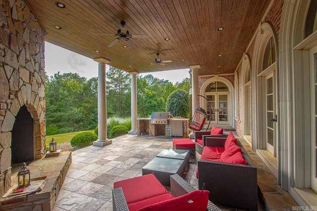 view of patio featuring french doors, exterior kitchen, ceiling fan, grilling area, and an outdoor living space with a fireplace