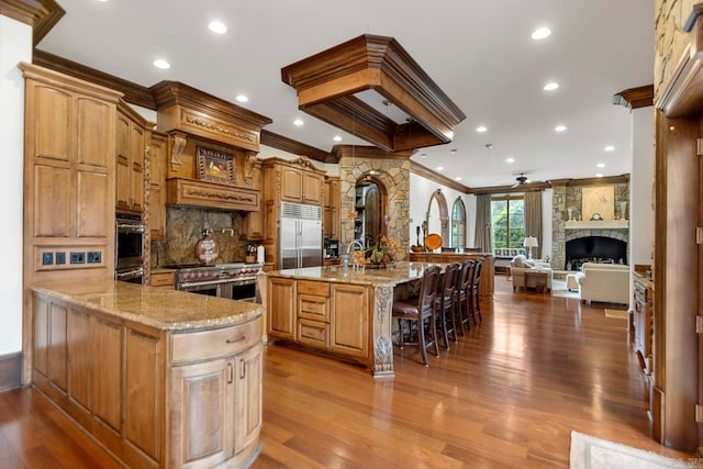 kitchen with premium appliances, light stone counters, crown molding, and decorative backsplash