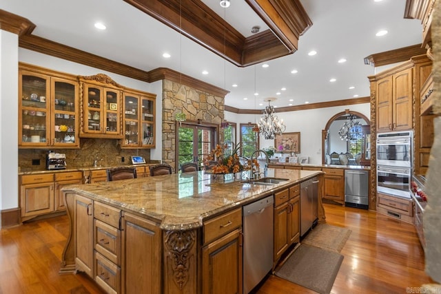 kitchen with a kitchen island with sink, appliances with stainless steel finishes, ornamental molding, and a sink