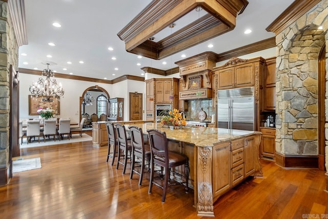 kitchen featuring a large island, ornamental molding, arched walkways, and appliances with stainless steel finishes