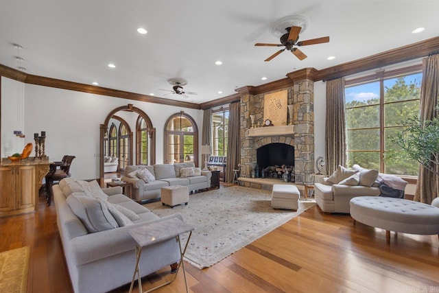 living area with a ceiling fan, a wealth of natural light, and ornamental molding