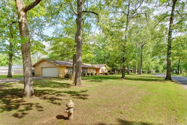ranch-style house featuring a front lawn, driveway, fence, and a garage