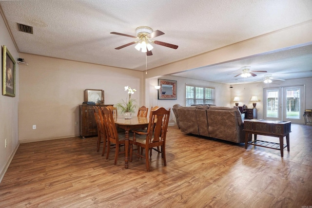 dining room with a ceiling fan, baseboards, light wood finished floors, and a textured ceiling