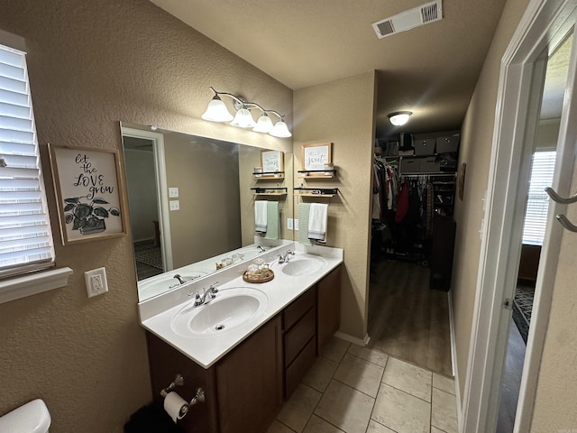 bathroom with a sink, a textured wall, and visible vents