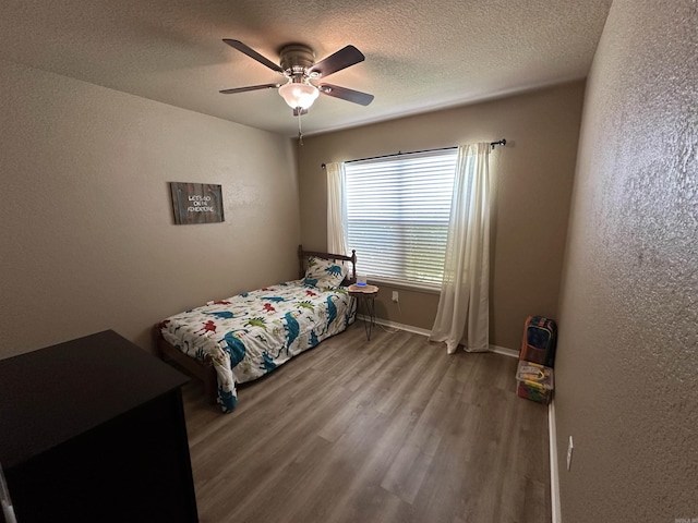 bedroom with a textured ceiling, a textured wall, and wood finished floors