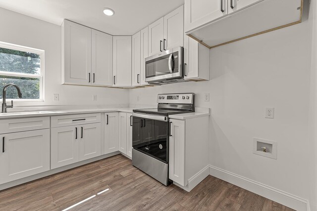 kitchen featuring light wood finished floors, light countertops, appliances with stainless steel finishes, and white cabinets