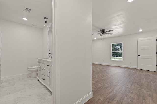 bathroom featuring toilet, a ceiling fan, visible vents, baseboards, and vanity