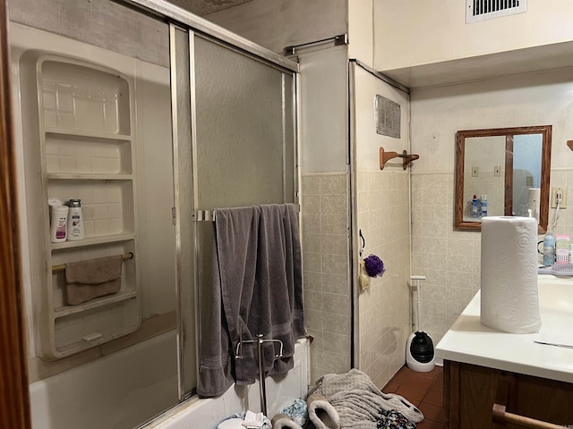 bathroom featuring tile walls, bath / shower combo with glass door, visible vents, tile patterned floors, and vanity