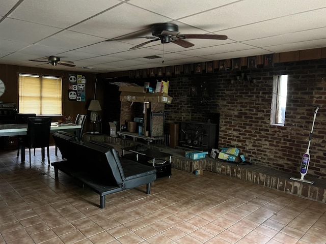 living area with a paneled ceiling, ceiling fan, and light tile patterned floors