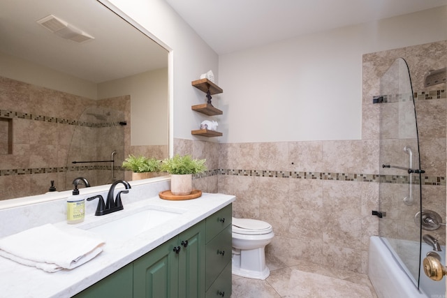 bathroom featuring tile walls, toilet, visible vents, vanity, and a wainscoted wall