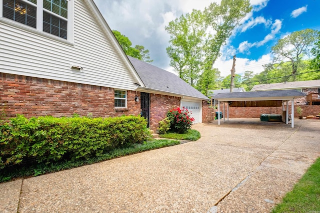 view of side of home with a garage, brick siding, and driveway