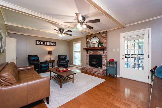 living room with wood finished floors, ornamental molding, beamed ceiling, a ceiling fan, and baseboards