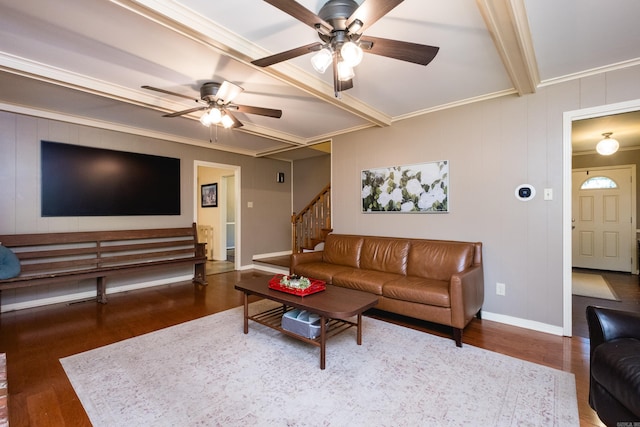 living area with beam ceiling, wood finished floors, ornamental molding, stairway, and a ceiling fan