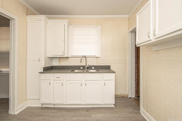 210 W 18th St, North Little Rock, AR 72114 - kitchen with white cabinetry, dark countertops, light wood-type flooring, and a sink