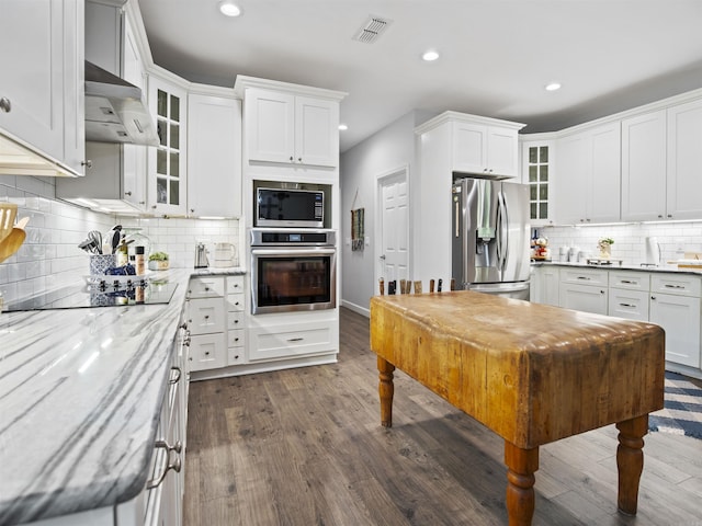 kitchen with wall chimney exhaust hood, stainless steel appliances, and recessed lighting