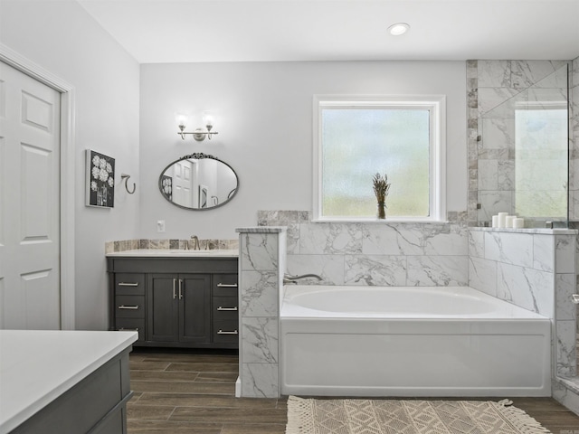 full bathroom featuring wood finished floors, vanity, recessed lighting, a garden tub, and a tile shower