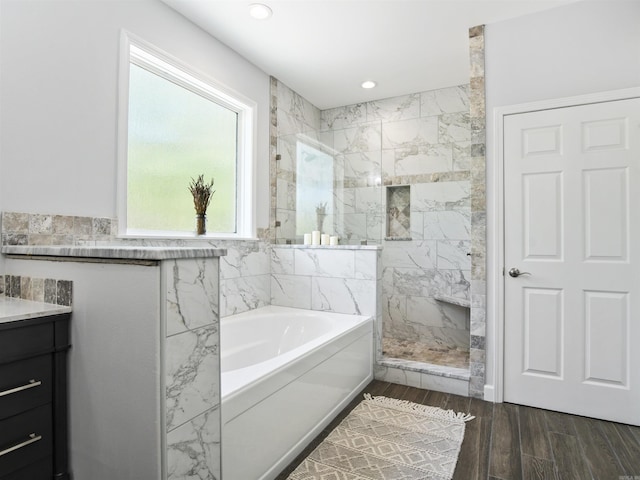 full bath featuring wood finished floors, a walk in shower, a bath, vanity, and recessed lighting