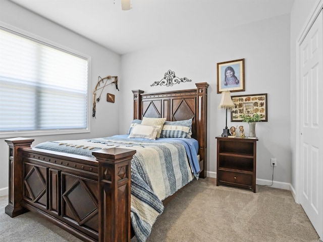 bedroom featuring light colored carpet, a closet, baseboards, and ceiling fan