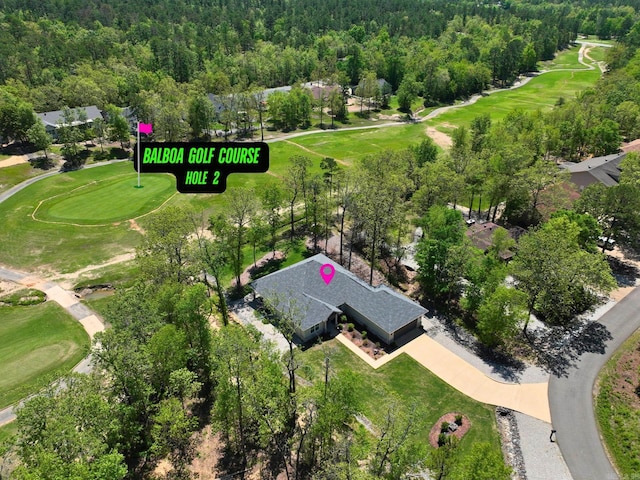 drone / aerial view featuring a wooded view and view of golf course