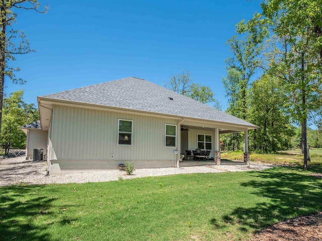 rear view of house with a yard, a shingled roof, a patio, and central AC unit