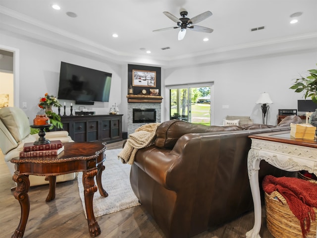 living room featuring a glass covered fireplace, ceiling fan, visible vents, crown molding, and dark wood-type flooring