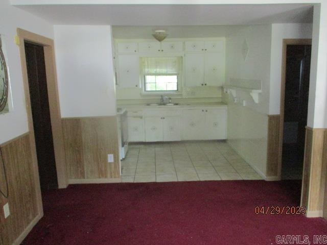 kitchen featuring light tile patterned floors, a sink, light carpet, light countertops, and white cabinets