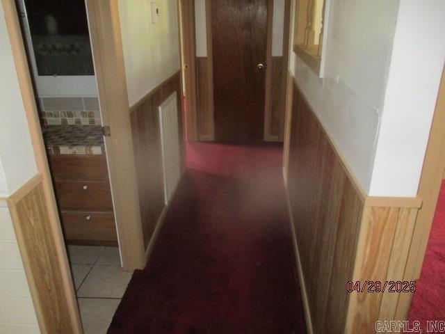 hall featuring tile patterned flooring and a wainscoted wall