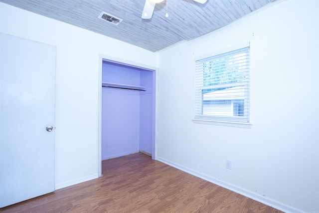 unfurnished bedroom with a closet, baseboards, ceiling fan, visible vents, and wood finished floors