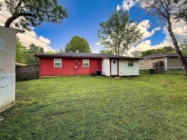 rear view of house featuring a yard, central air condition unit, and fence