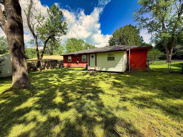 rear view of property featuring a yard and a fenced backyard