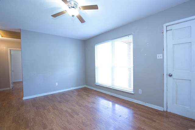 spare room featuring baseboards, ceiling fan, and wood finished floors