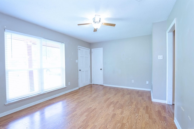 empty room featuring light wood-style flooring, baseboards, and ceiling fan