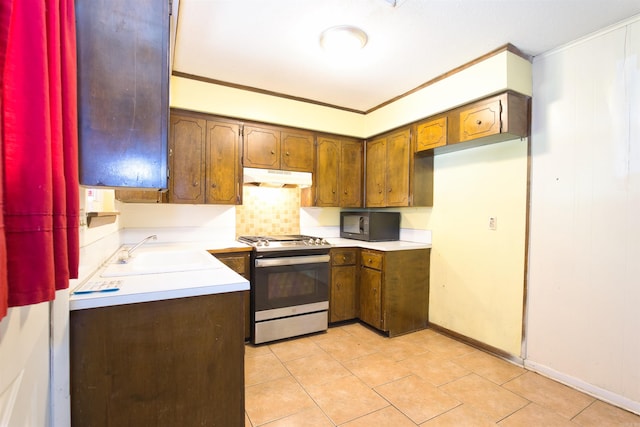 kitchen featuring gas range, light countertops, a sink, and under cabinet range hood
