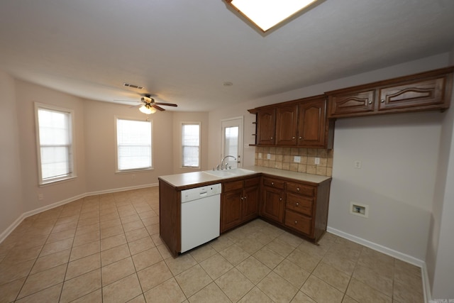 kitchen with a sink, a peninsula, visible vents, a ceiling fan, and white dishwasher