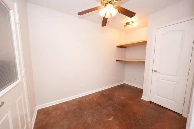 interior space with baseboards, ceiling fan, and concrete flooring