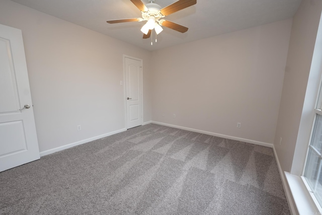 carpeted spare room featuring baseboards and a ceiling fan