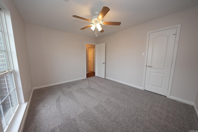 unfurnished bedroom with baseboards, multiple windows, a ceiling fan, and carpet floors